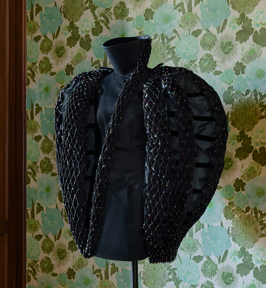 The Caged Bird, black couture dress by Ronald van der Kemp against floral wallpaper