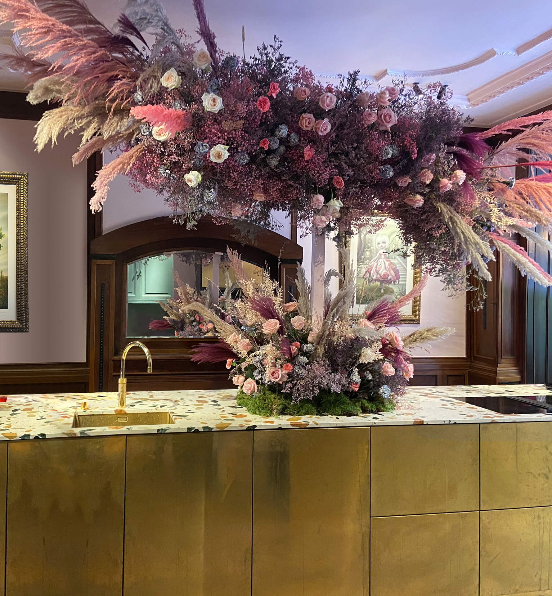 Large dried flower installation above a brass kitchen island