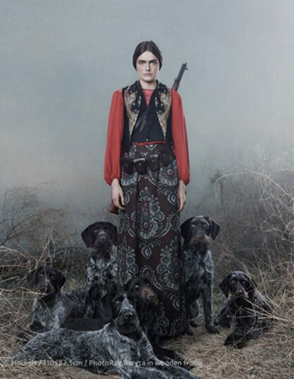 Photograph by Frieke Janssens: woman in embroidered clothing surrounded by hunting dogs