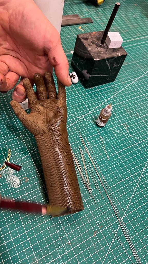 Craftsman sculpting a wooden hand on a cutting mat